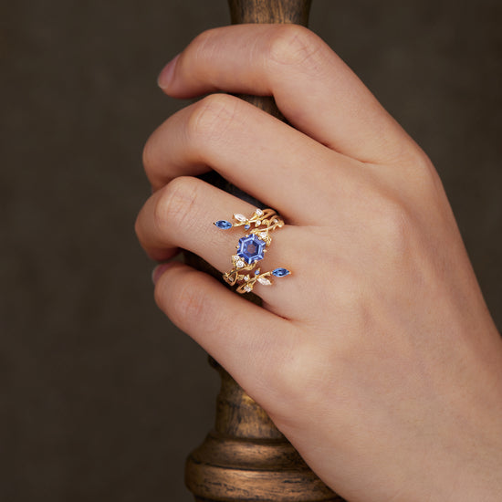 Hand wearing Claire hexagon sapphire vine ring set with gold and moissanite accents