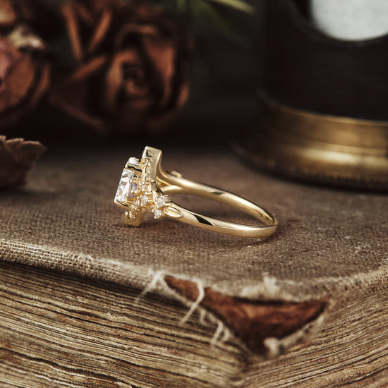 Floral moissanite ring with tanzanite, set in yellow gold on textured surface.