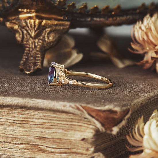 Detailed nature-inspired ring featuring pear-cut alexandrite with floral accents.