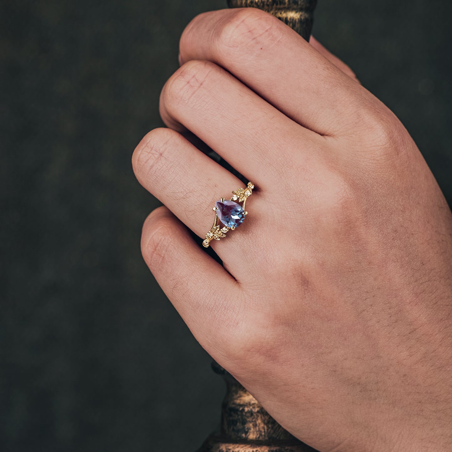 Nature-inspired yellow gold ring with pear-cut alexandrite and vine details.