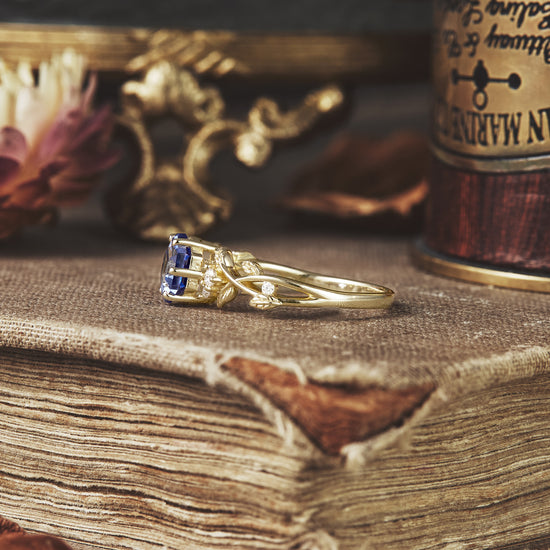 Hexagon sapphire ring with intricate vine design and moissanite details on gold.