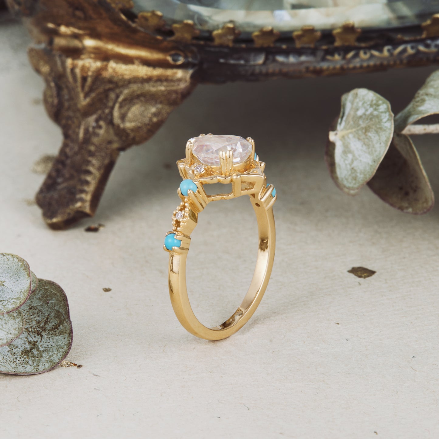 Unique turquoise and moissanite ring in gold, featuring pear cut center and delicate accents.