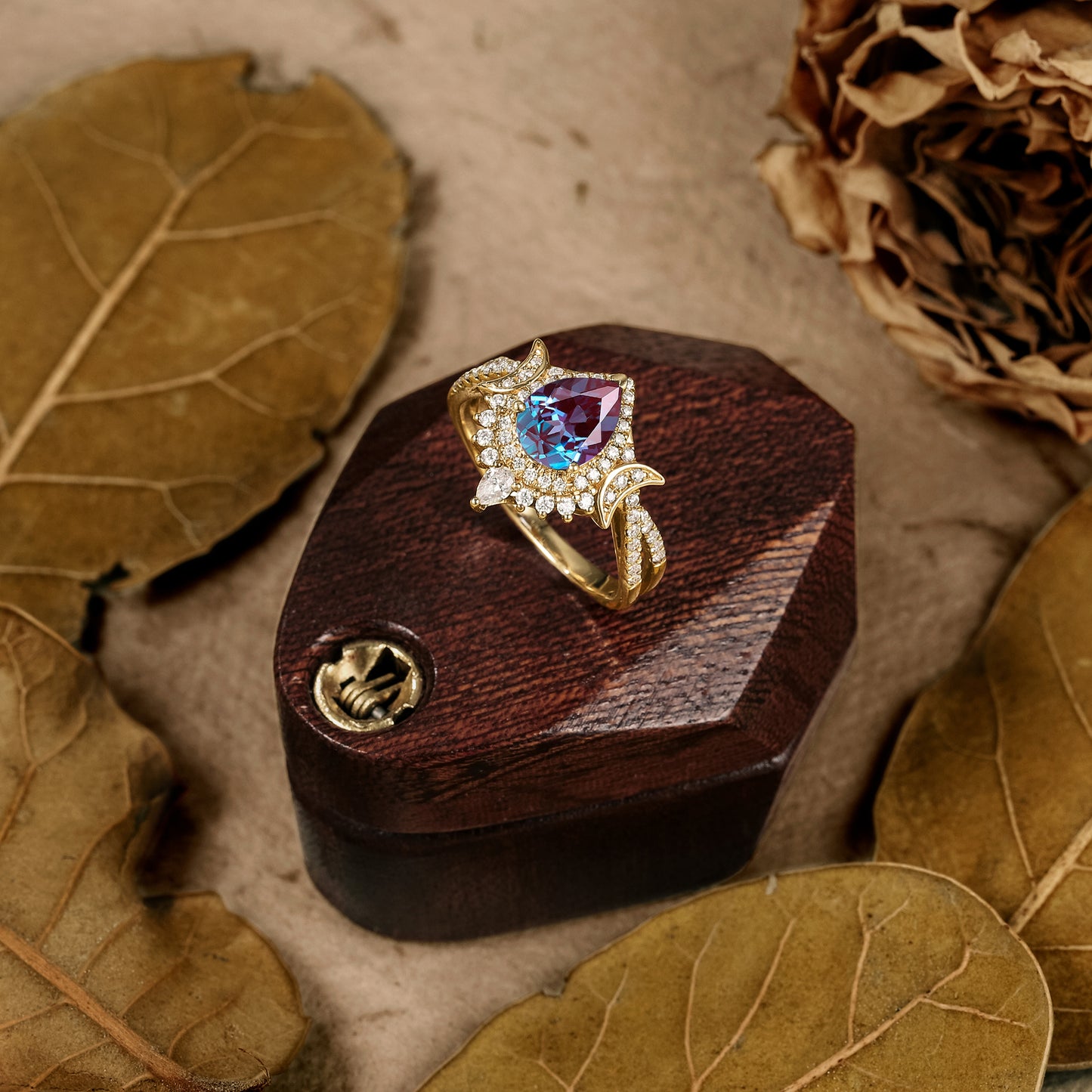 Alexandrite ring with moissanite accents and gold band on wooden display box.