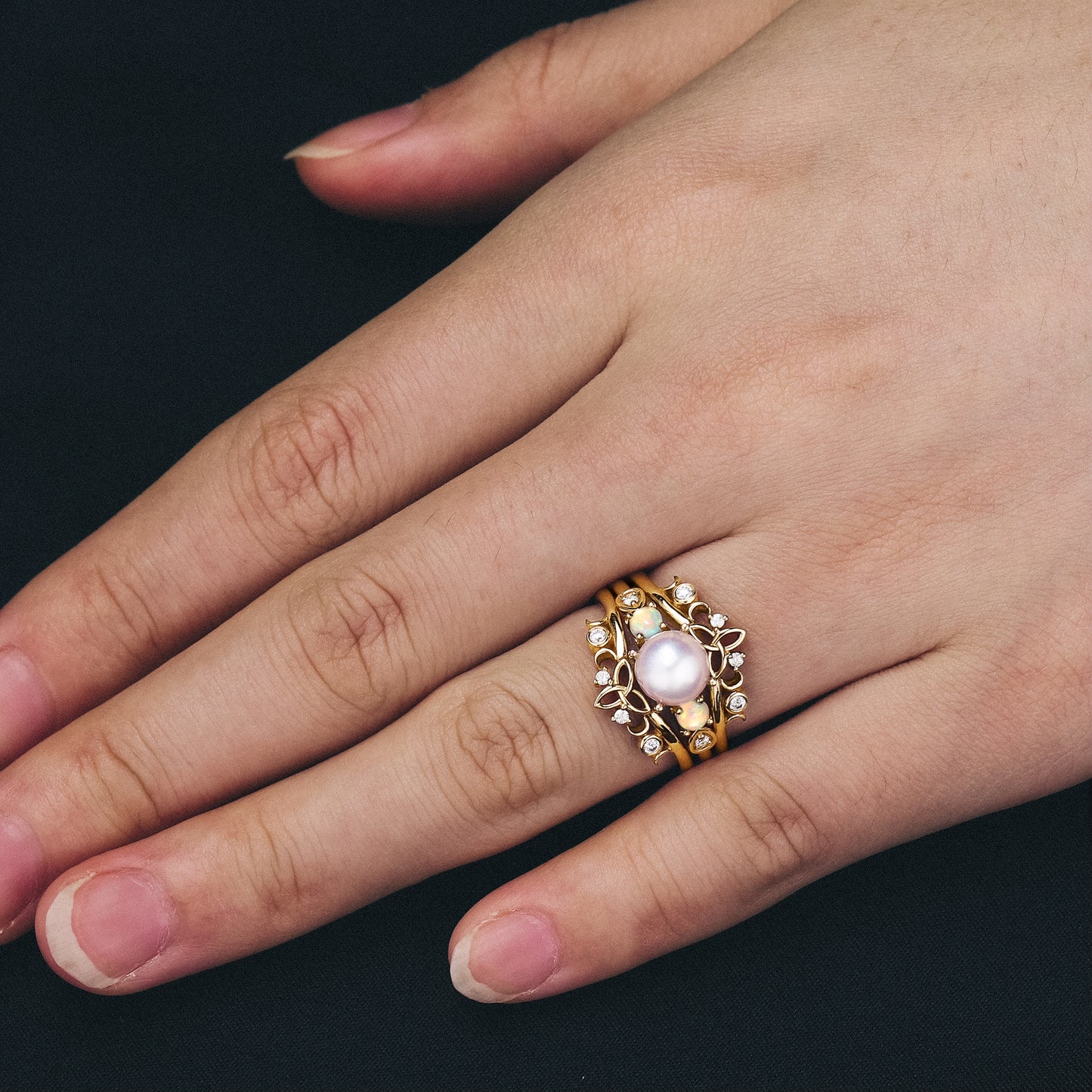 Gold engagement ring set with Akoya pearl, opals, and moissanite in floral design.