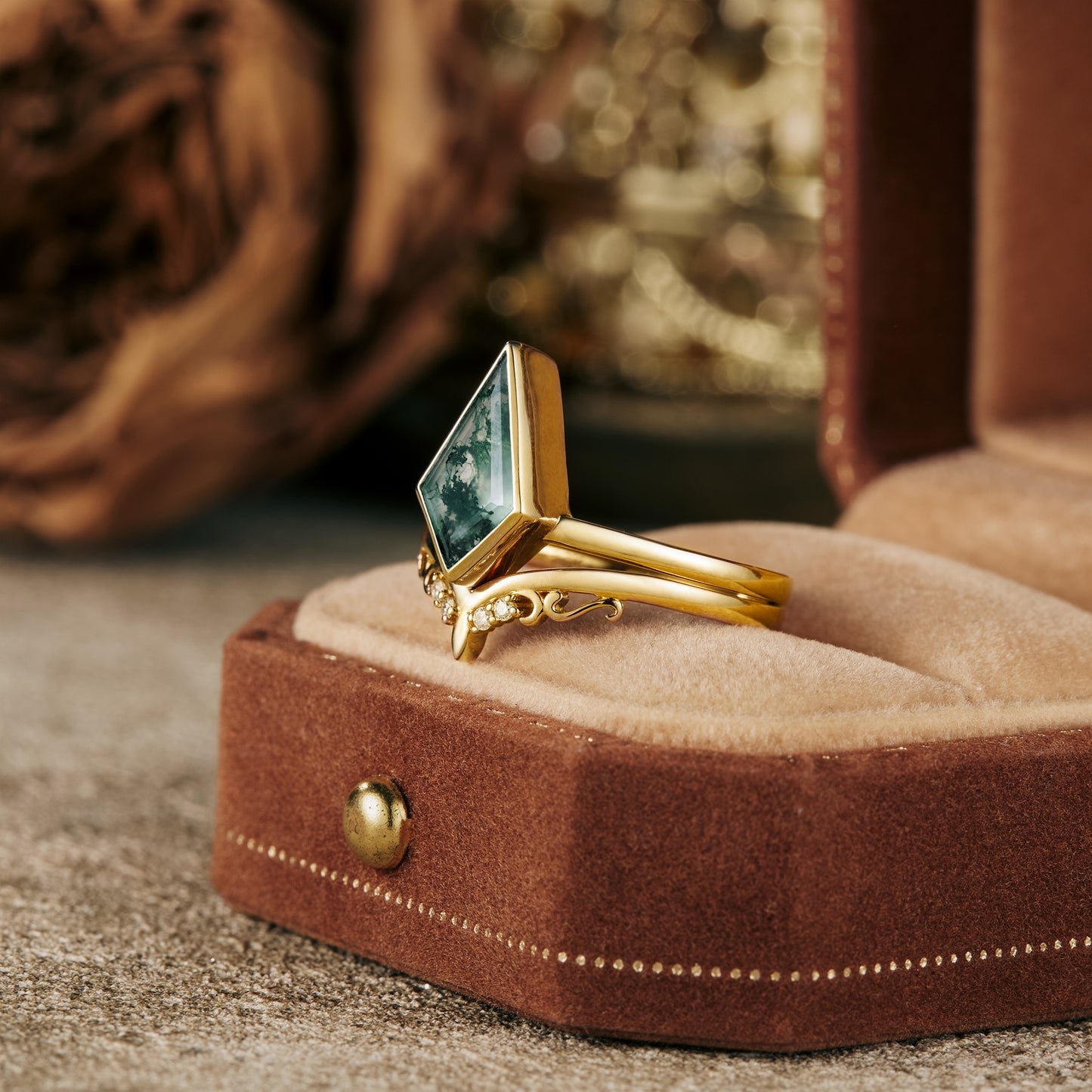 Unique kite-cut moss agate ring set in textured gold band on display.