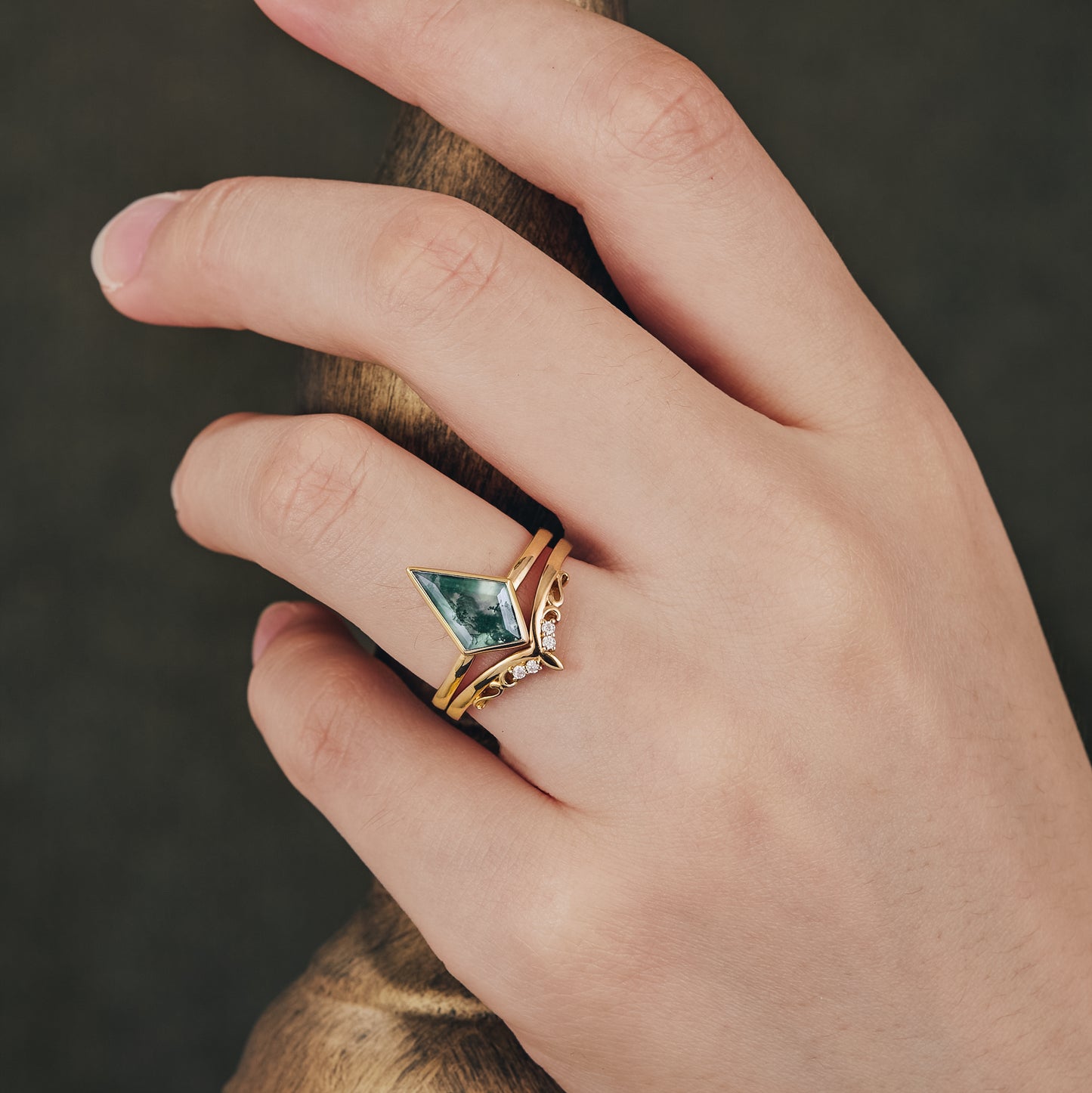 Kite-cut moss agate ring set with diamond accents on a hand.