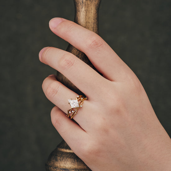 Unique kite cut moissanite engagement ring on hand with twisted gold band and accent stones