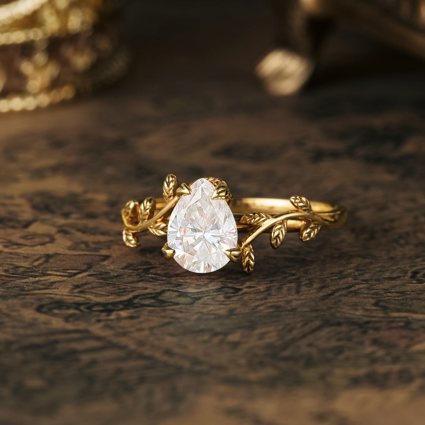 Elegant pear moissanite ring with delicate gold leaf accents and floral design.