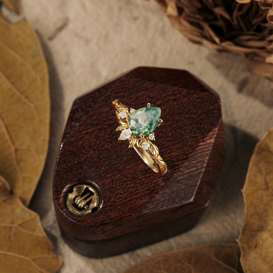 Nature-inspired moss agate pear ring with diamond accents in golden leaf setting.