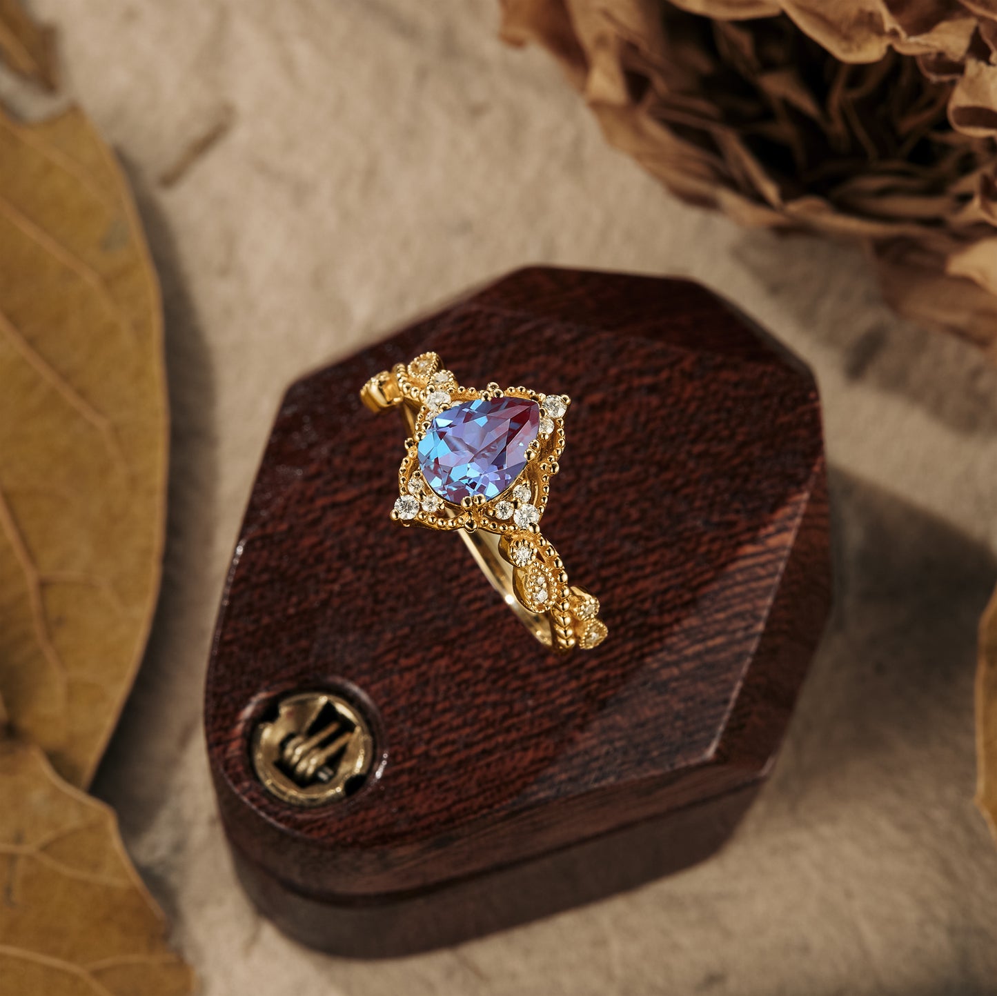 Nature-inspired pear cut alexandrite engagement ring with moissanite on wooden display