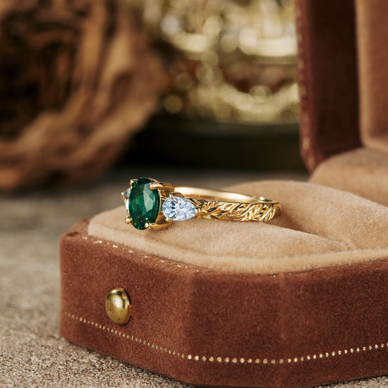 Elegant emerald and aquamarine engagement ring on velvet display.