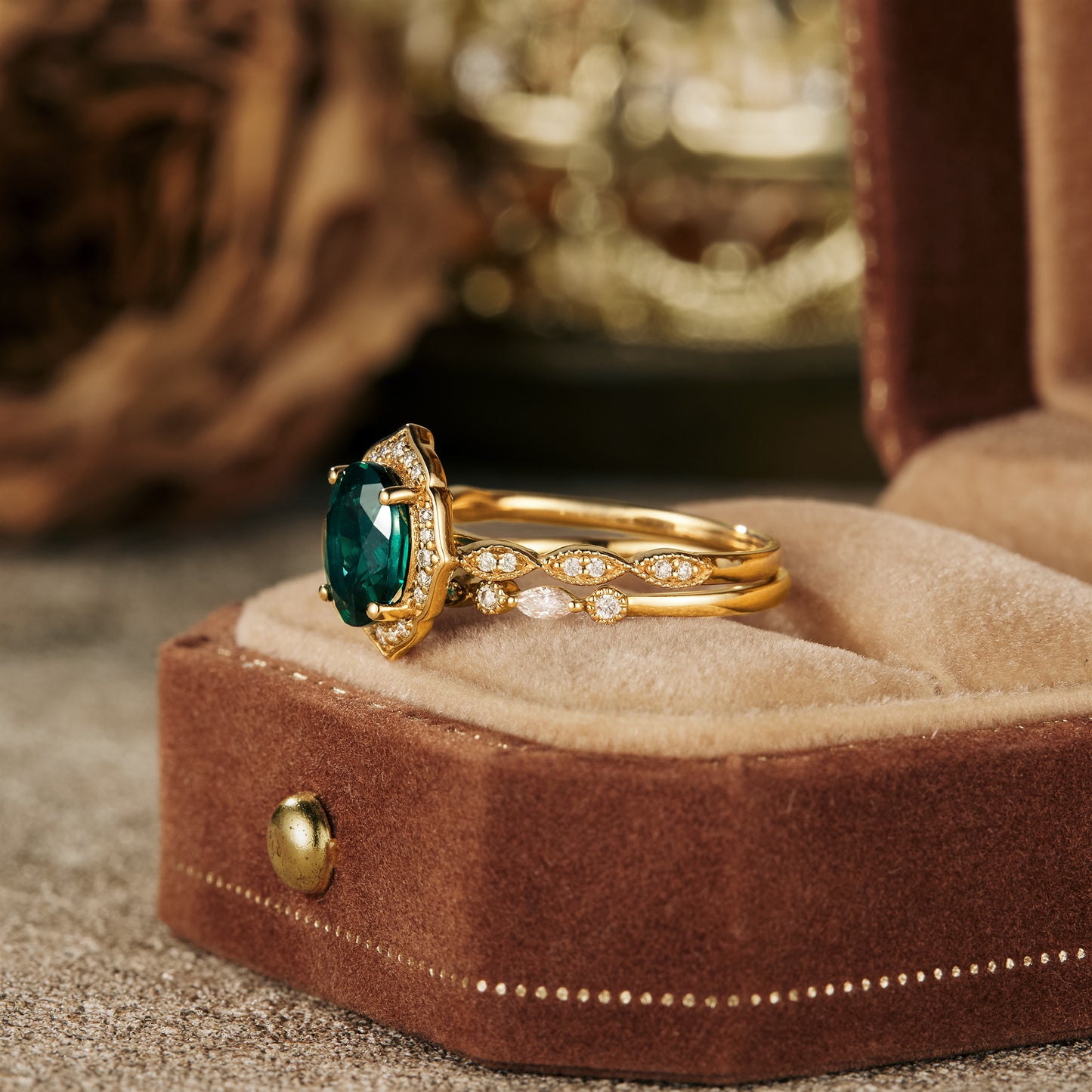 Vintage emerald halo ring set in yellow gold with sparkling moissanite accents.